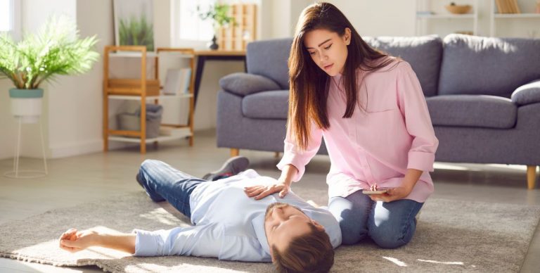 o femeie tanara se pregateste sa sune la ambulanta dupa ce partenerul ei a lesinat in casa