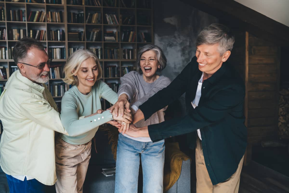 patru prieteni fericiti, în picioare și cu mâinile împreunate