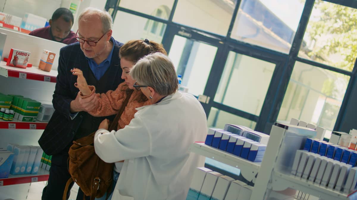 femeie tanara in pragul lesinului e sprijinita de un barbat si de angajata farmaciei in care se afla